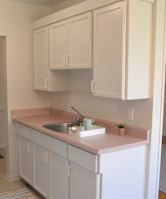 A kitchen with white cabinets and a white refrigerator.
