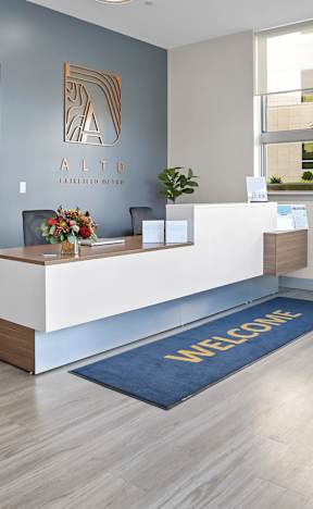 A reception area with a white desk and a blue rug.