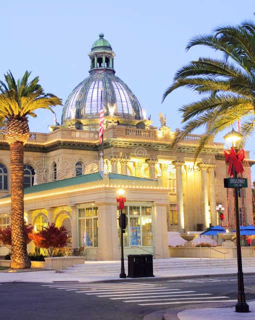A large building with a dome and palm trees in front.