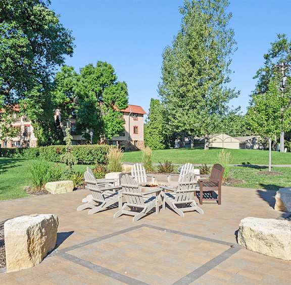 A patio with a table and chairs surrounded by rocks and plants.