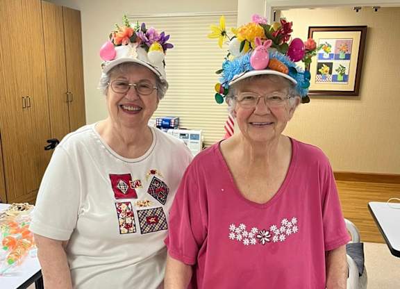 Two elderly women wearing floral hats at River Commons Senior Living, Redding, 96002