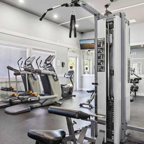 A gym with a variety of exercise equipment including treadmills, stationary bikes, and weights. at Deer Crest Apartments, Broomfield, CO