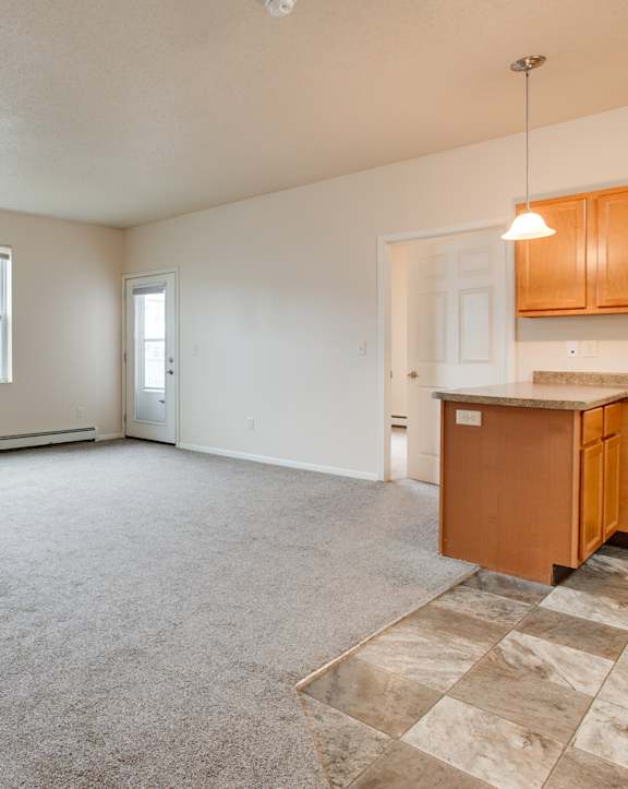 A spacious room with a window, a door, and a kitchenette. at Boulder Ridge Apartments, Fargo, 58104