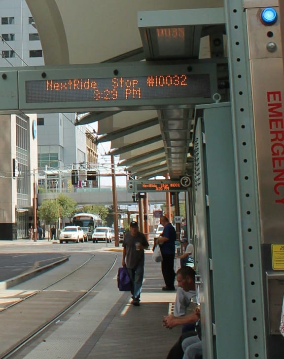 a tram stop on a street in a city with tall buildings