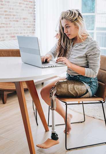 A woman is sitting at a table using a laptop.