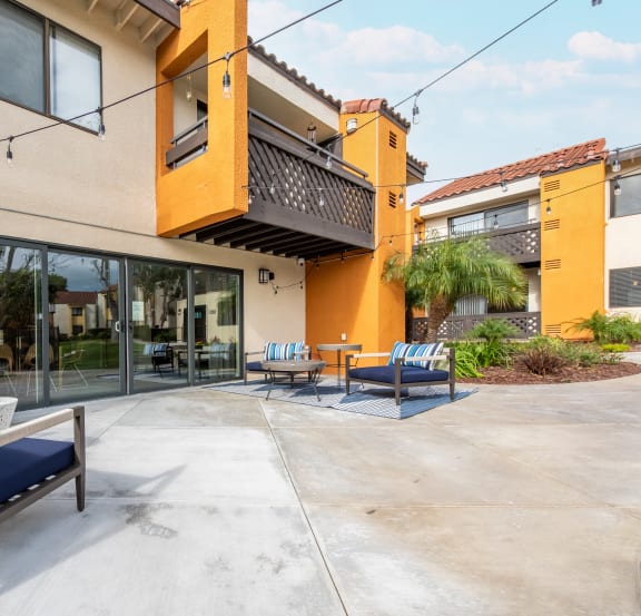 a patio with chairs and tables and a building with glass doors