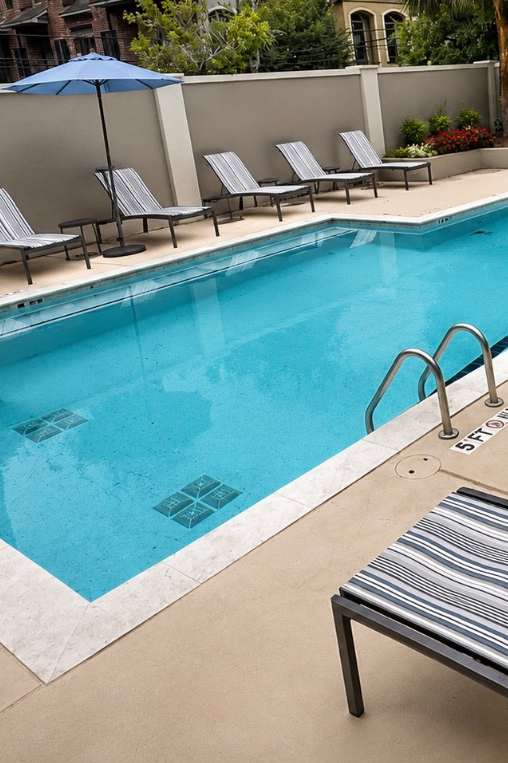 A pool with a metal ladder and lounge chairs.
