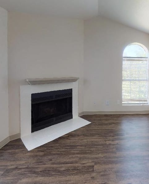 an empty living room with a fireplace and a kitchen