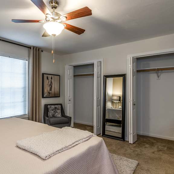 A bedroom with a bed, a chair, and a ceiling fan.