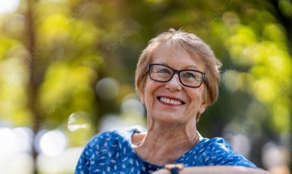 an older woman sitting on a bench in the park