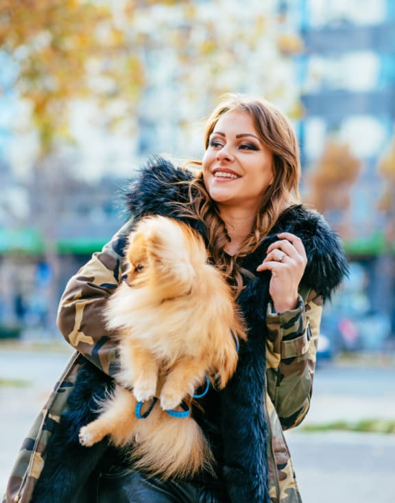 a woman wearing a camouflage jacket holding a dog