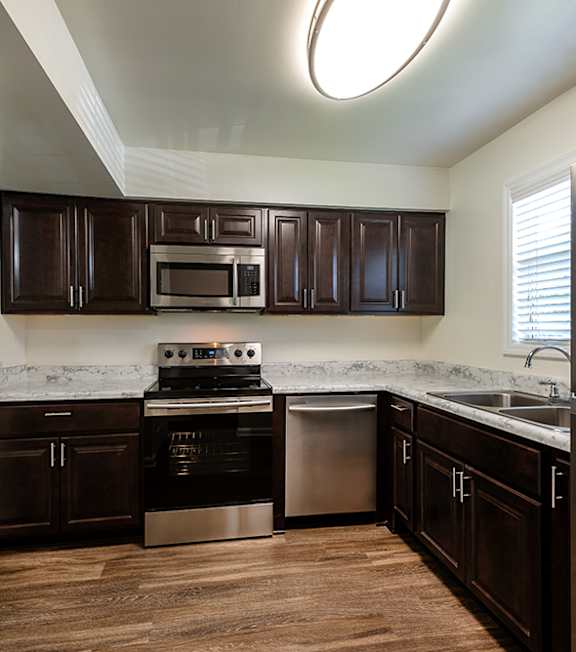 A kitchen with dark brown cabinets and stainless steel appliances.