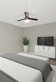 A bedroom with a bed, a television, and a plant.