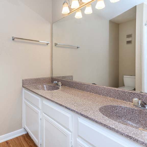A bathroom with a granite countertop and a double sink.