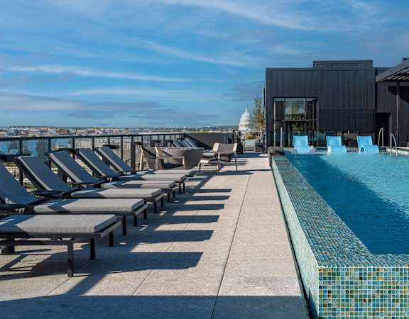 A large outdoor swimming pool with a metal roof and lounge chairs.