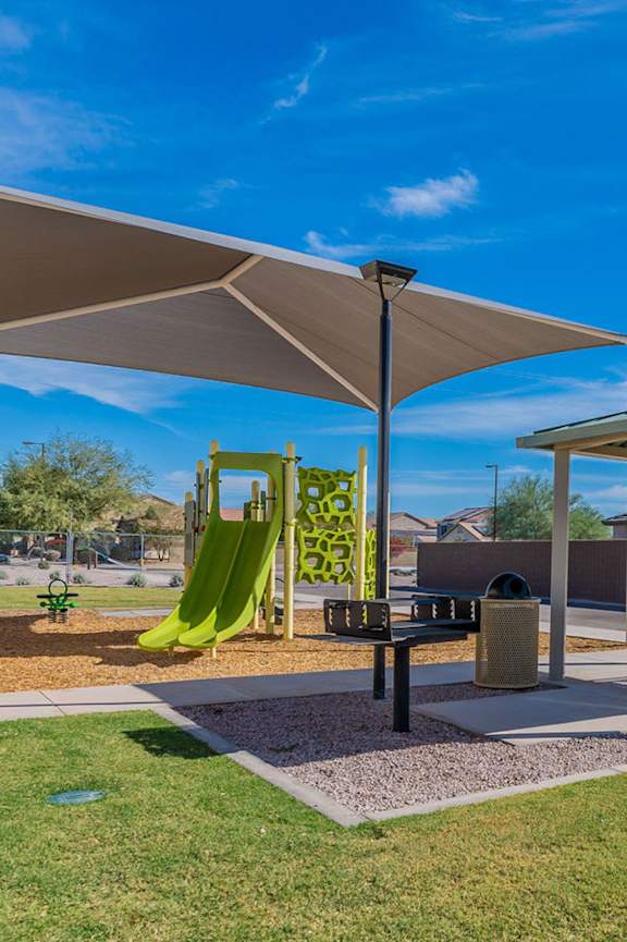 A playground with a green slide and a canopy.