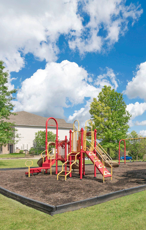 A playground with a red swing set and a yellow slide.