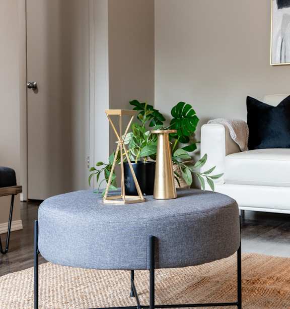 A living room with a white couch and a painting on the wall.