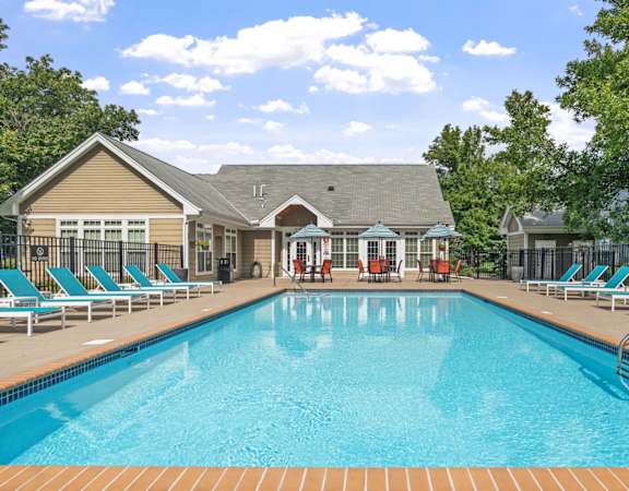 A large swimming pool with lounge chairs and a building in the background.