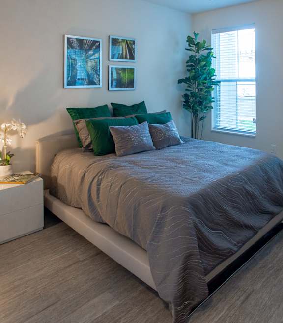A bedroom with a bed, pillows, a nightstand with a lamp, and a plant at 42 Hundred On The Lake, St Francis, WI