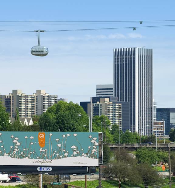 A cable car is suspended in the air over a cityscape.
