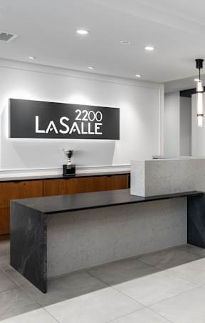 a modern hotel lobby with a large reception desk and blue chairs at 2200 LaSalle, St Louis, MO, 63104