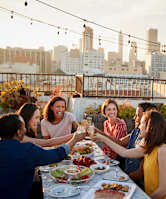 a group of people sitting around a table eating and drinking wine