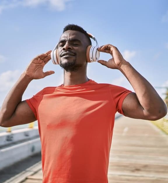 a man standing on a pier with his hands on his ears