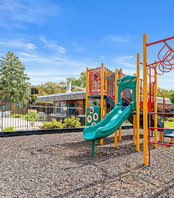 A playground with a green slide and orange climbing structure.