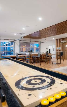 A shiny pool table with a white cloth and yellow balls is in the middle of a room with a wooden ceiling.