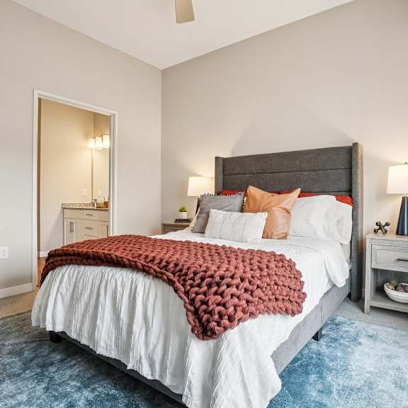 A bedroom with a large bed and a blue rug.
