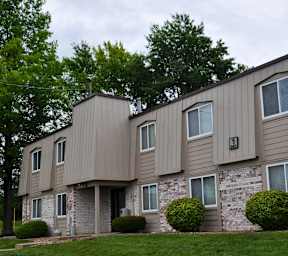 The exterior of Park 25 Apartments, featuring a well-maintained lawn with green grass and a tree near the front entrance.