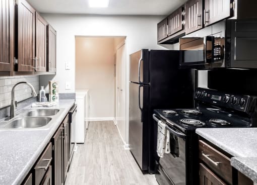 Galley kitchen with black appliances located at Addison on Cobblestone located in Fayetteville, GA 30215
