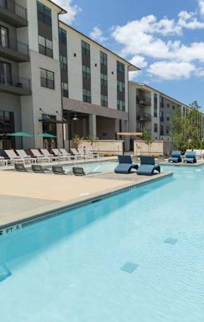 A large swimming pool surrounded by lounge chairs and umbrellas.