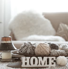 A table with balls of yarn and a "Home" sign on it.