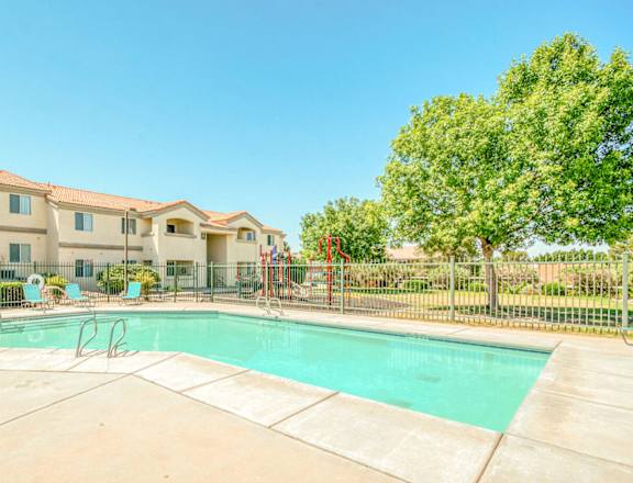 a swimming pool with a fence and apartment buildings in the background