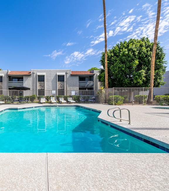 A swimming pool in front of a building with palm trees.