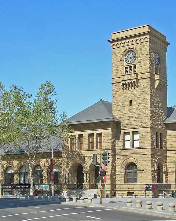 A large building with a clock tower in the middle of a city street.
