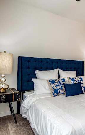 A bedroom with a large bed and two lamps.