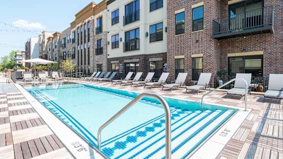 A swimming pool surrounded by lounge chairs and buildings.