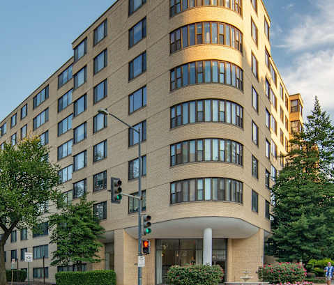 A street view of a curved building with a crosswalk in front of it.