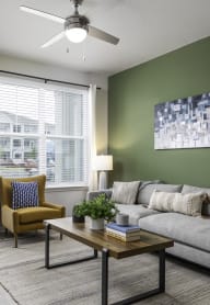 a living room with green walls and a ceiling fan