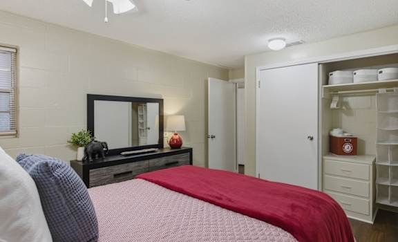 A bedroom with a bed, dresser, and a ceiling fan.