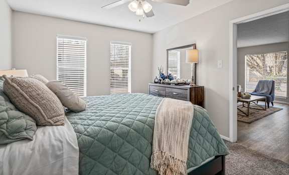 A bedroom with a bed, a ceiling fan, and a chair.