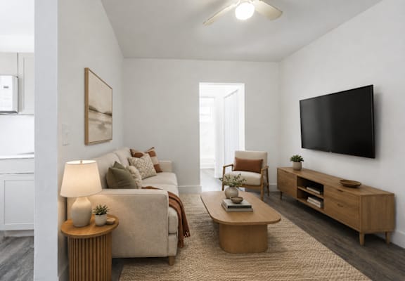 A living room with a couch, a chair, a coffee table, and a television.