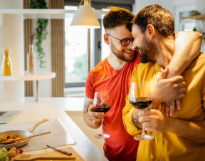 a couple of two men hugging cooking and drinking wine