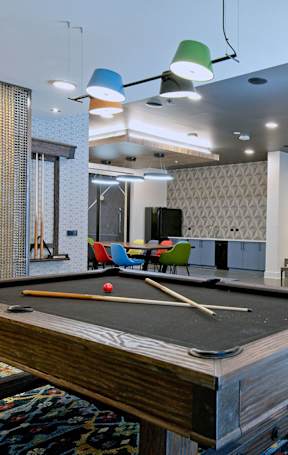 A pool table is in the middle of a room with a fireplace and a TV.