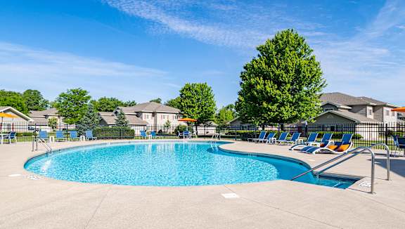 A large swimming pool surrounded by lounge chairs and trees.