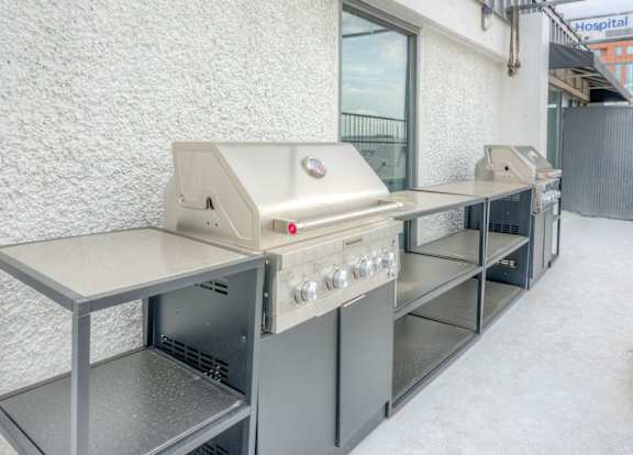 A row of stainless steel grills are lined up on a white wall.