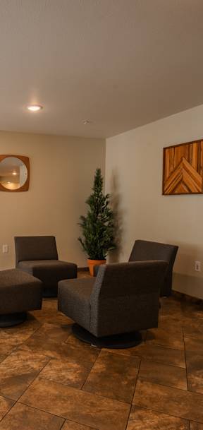 A living room with brown tiled floors and a small Christmas tree.